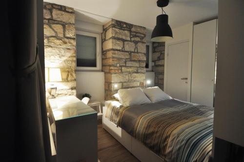 a bedroom with a bed and a stone wall at Amfora Deluxe Studio in Pula