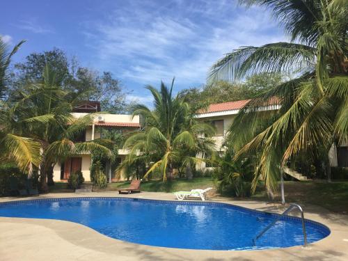 una piscina frente a una casa con palmeras en Las Colinas de Playas del coco, en Coco