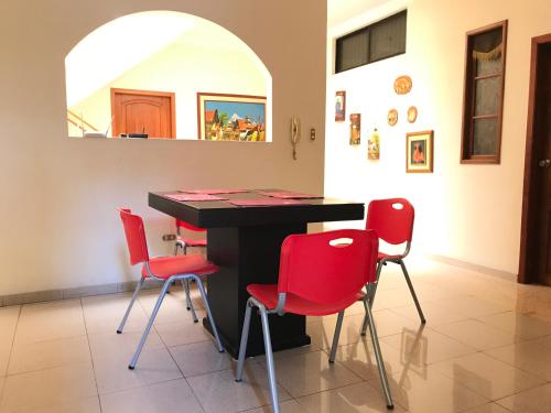 Habitación con mesa y 4 sillas rojas en Casa Canelos en Guayaquil