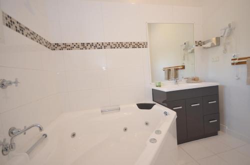 Baño blanco con bañera y lavamanos en Central Springs Inn, en Daylesford