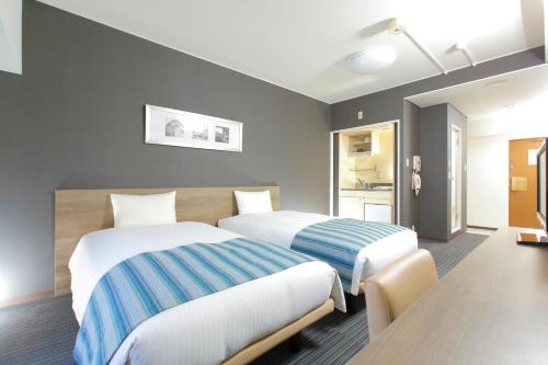a hotel room with two beds and a kitchen at HOTEL MYSTAYS Otemae in Osaka