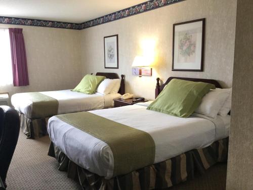 a hotel room with two beds with green sheets at Americas Best Value Inn and Suites Saint Charles in St. Charles