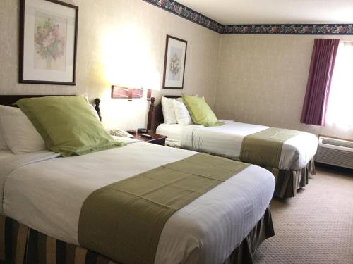 a hotel room with two beds with green pillows at Americas Best Value Inn and Suites Saint Charles in St. Charles