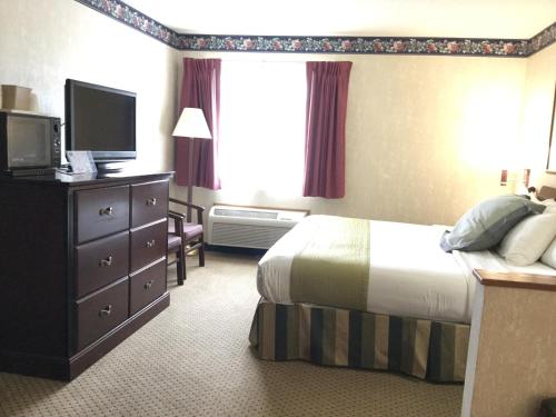 a hotel room with a bed and a flat screen tv at Americas Best Value Inn and Suites Saint Charles in St. Charles