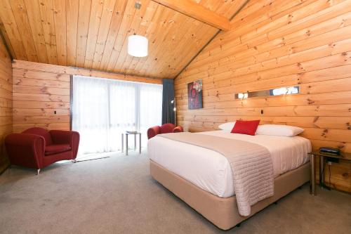 - une chambre avec un lit dans une pièce en bois dans l'établissement Lockwood Manor Motel, à New Plymouth