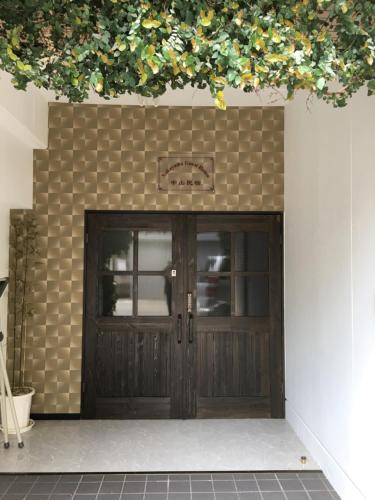 a garage with a wooden door with flowers above it at Osaka Nakayama Guesthouse in Osaka