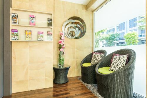 two wicker chairs and a vase with flowers on a porch at Fragrance Hotel - Viva in Singapore