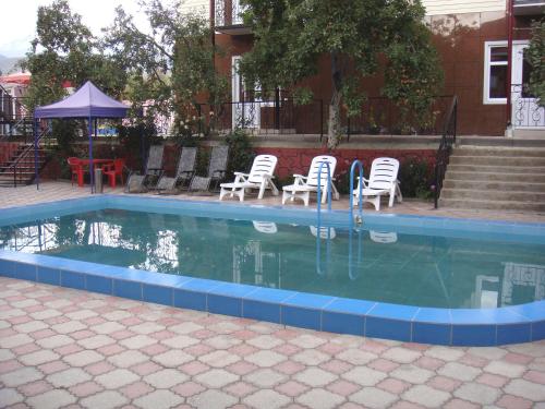 a swimming pool with chairs and a table and stairs at Mini-pansionat Maksat in Cholpon-Ata