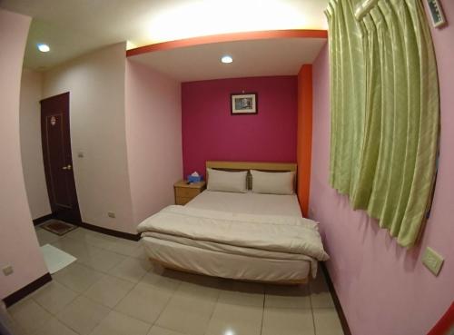 a bedroom with a bed in a pink wall at ZaiXiang in Tamsui