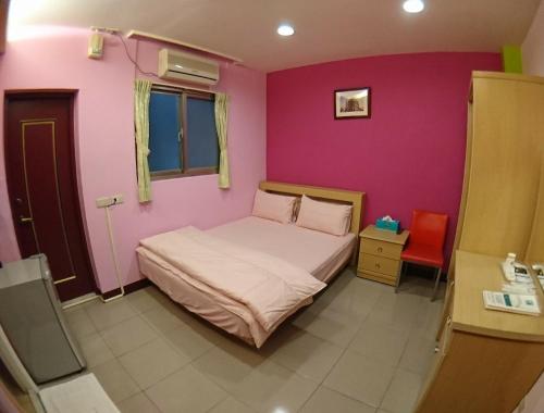 a bedroom with a bed and a pink wall at ZaiXiang in Tamsui