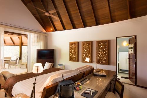 a bedroom with a bed and a desk and a table at Constance Halaveli in Hangnaameedhoo