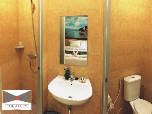 Un baño con lavabo, inodoro y espejo. en The Alley City Hotel, en Sanur