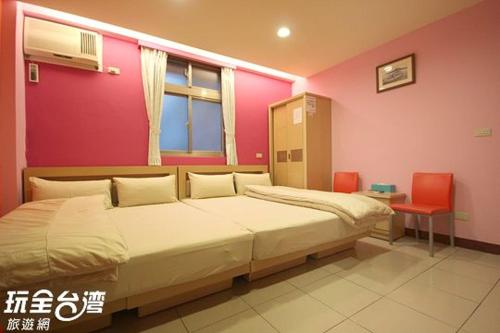 a bedroom with two beds and a pink wall at ZaiXiang in Tamsui