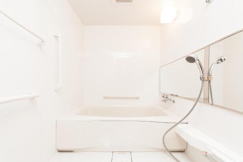 a white bath tub sitting next to a white sink at HOTEL MYSTAYS Sakaisuji Honmachi in Osaka