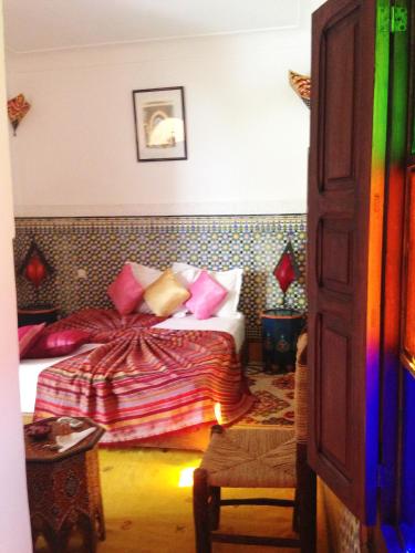 a bedroom with a bed with colorful pillows at Riad Mehdia in Marrakech