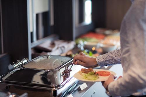 a person holding a plate of food next to a stove at Hotel Sophia by Tartuhotels in Tartu