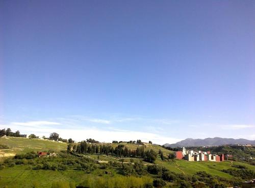 a green field with a building on a hill at Taza Organic Garden with view park and restaurant in Taza