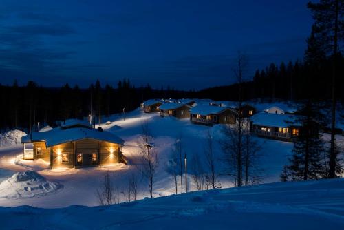 un gruppo di case nella neve di notte di Valkea Arctic Lodge a Pello