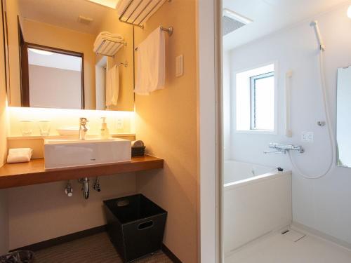 a bathroom with a sink and a tub and a mirror at Hotel Bliss Villa Hasami in Hasami