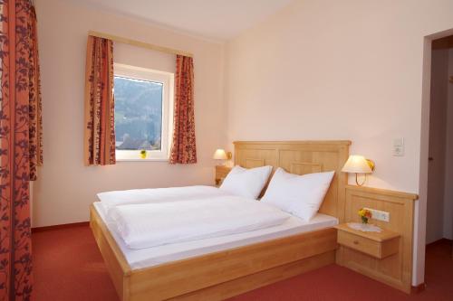 Schlafzimmer mit einem Bett mit weißer Bettwäsche und einem Fenster in der Unterkunft Hotel Pariente in Schladming