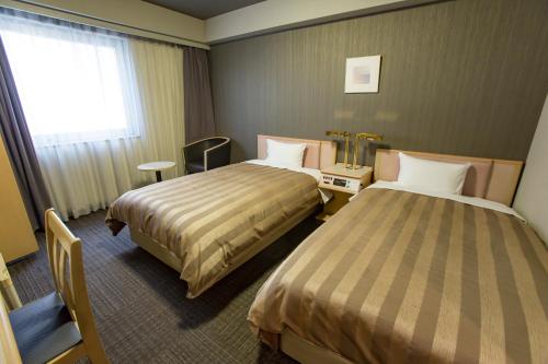 a hotel room with two beds and a window at Hotel Route-Inn Tokyo Ikebukuro in Tokyo