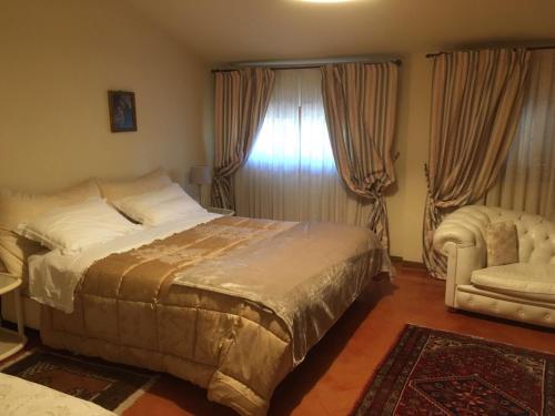 a bedroom with a bed and a chair and a window at B&B Elda Country House in Chiassa Superiore