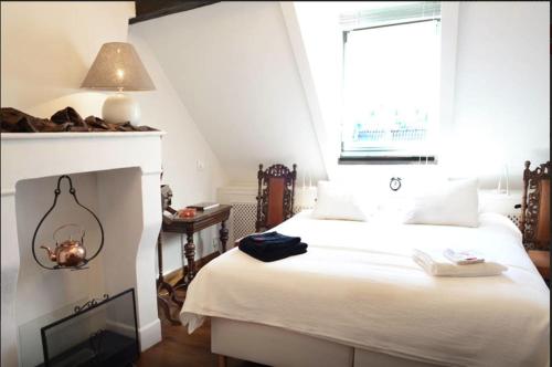 a bedroom with a white bed and a fireplace at Artagnan in Maastricht
