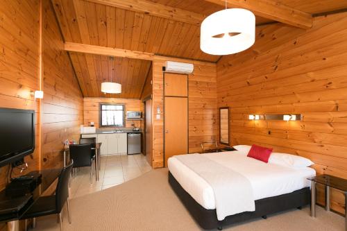 a bedroom with a bed and a desk and a television at Lockwood Manor Motel in New Plymouth