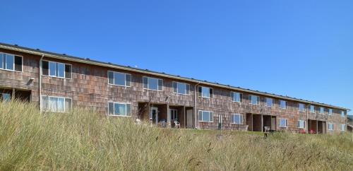 a building on top of a hill with tall grass at Silver Sands in Rockaway Beach