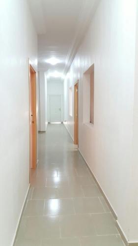 an empty hallway with white walls and a white tile floor at Muntala's Guest House in Hohoe