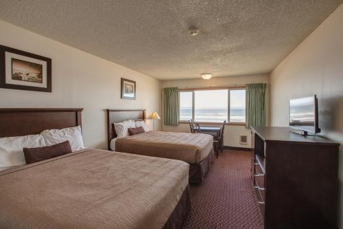 a hotel room with two beds and a flat screen tv at Silver Sands in Rockaway Beach