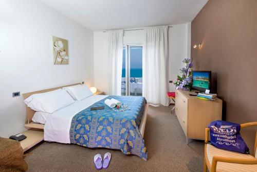 una camera con letto, TV e sedia di Hotel & Residence Medi Garden ad Alba Adriatica