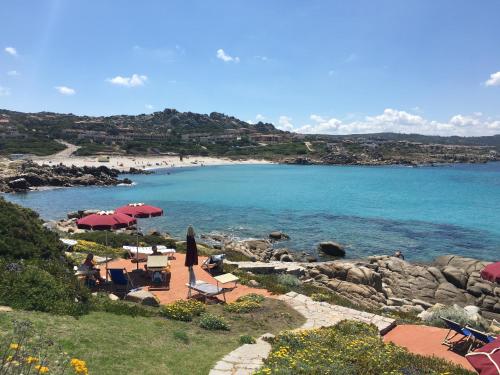 a beach with chairs and umbrellas and the ocean at Club Esse Shardana in Santa Teresa Gallura