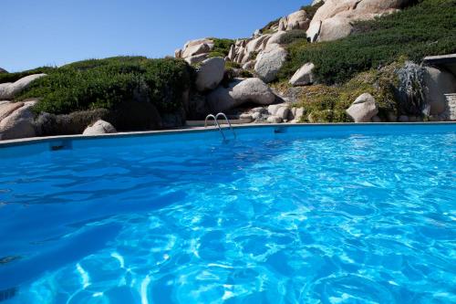 a swimming pool with blue water in front of a mountain at Club Esse Shardana in Santa Teresa Gallura