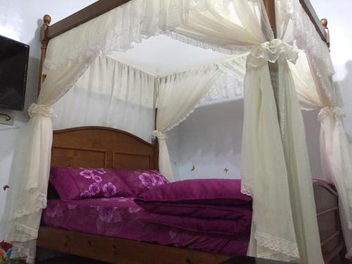 鳳林鎮的住宿－康晨有機果園民宿，一间卧室配有一张带紫色床单的天蓬床