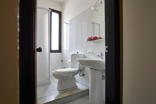 Baño blanco con aseo y lavamanos en Hotel Mazzurco en Cesarò