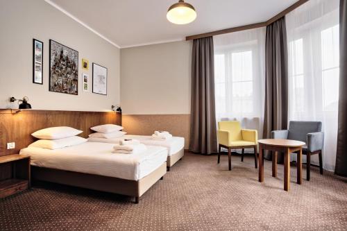 a hotel room with two beds and a table and chairs at Daniel Griffin Aparthotel by Artery Hotels in Krakow