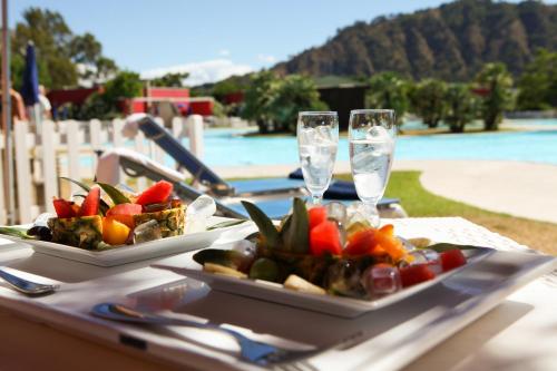 a table with two plates of food and wine glasses at Club Esse Sunbeach in Squillace