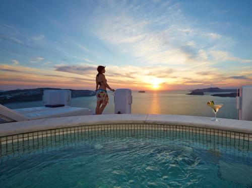 a woman is standing next to a swimming pool at Athermi Suites - Adults Only in Megalokhori