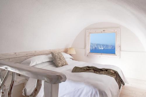 a white bedroom with a bed and a window at Athermi Suites - Adults Only in Megalokhori