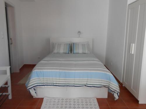 uma cama com um cobertor listrado num quarto em Studio Bibi em Gouvinhas