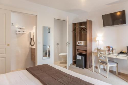 um quarto de hotel com uma cama, uma secretária e uma casa de banho em Logis Auberge le petit pont em Tennie