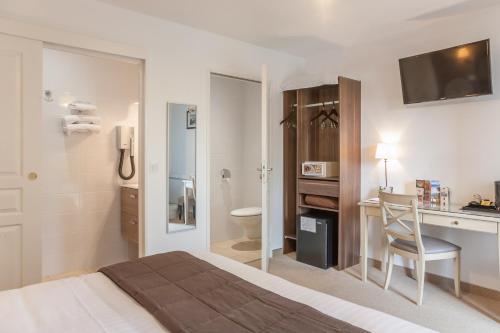 a hotel room with a bed and a desk and a bathroom at Logis Hotel-Restaurant "Auberge Le Petit pont" in Tennie