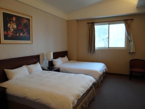 a hotel room with two beds and a window at Wuzhou Hotel in Hualien City