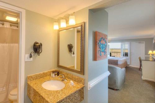 a bathroom with a sink and a mirror and a bed at Shutters on the Banks in Kill Devil Hills