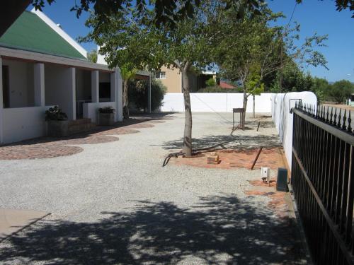 a house with a fence and a tree in a driveway at Aant Dorpseind in Vanrhynsdorp