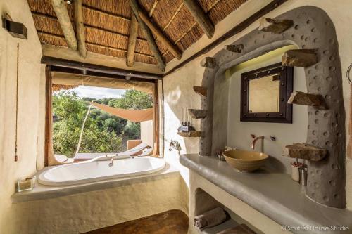 baño con bañera, lavabo y ventana en Safari Lodge - Amakhala Game Reserve, en Reserva de Amakhala