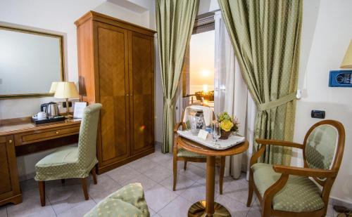 a room with a desk and a table and chairs at Grand Hotel Victoria in Bagnara Calabra