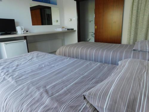 a hotel room with two beds with striped sheets at Chelford Guesthouse in Marthall