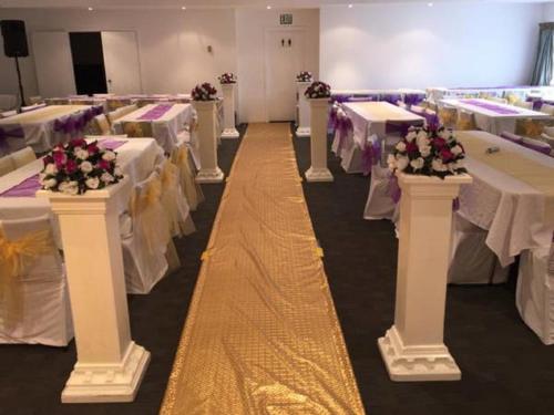 a banquet hall with white tables with flowers on them at Manukau Hotel & Conference Centre in Auckland